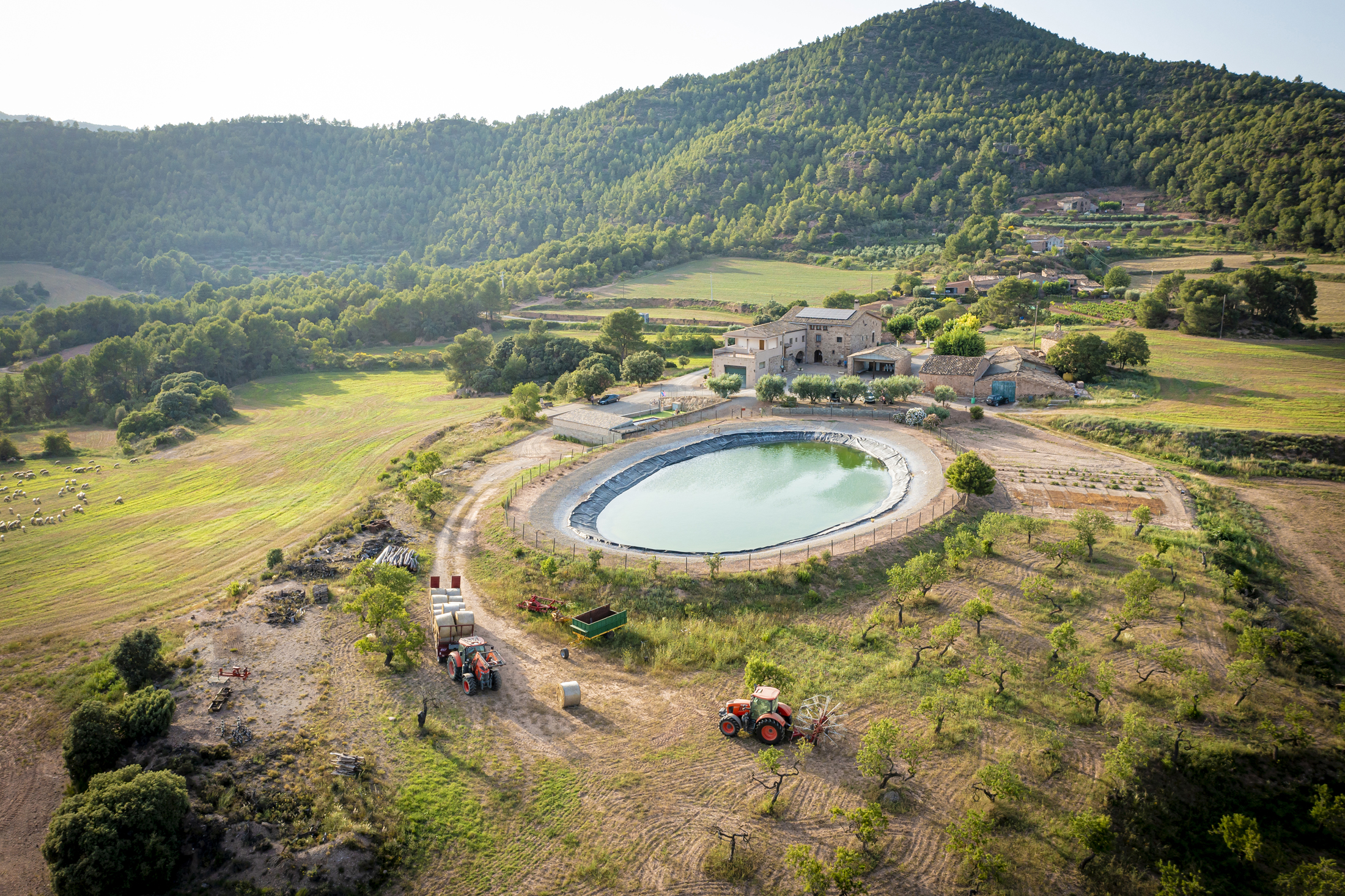 Vista panoràmica de Can Fontanelles envoltada de bosc, muntanya i un entorn rural